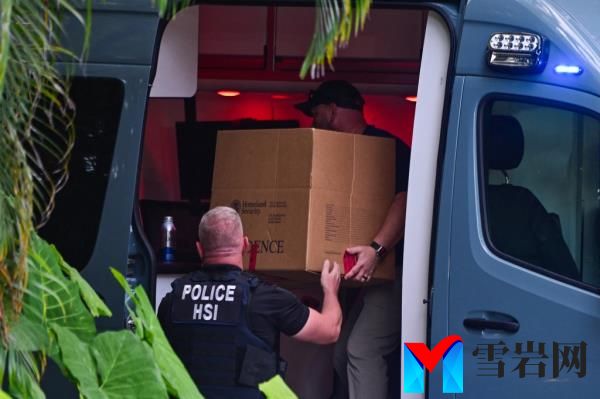 Homeland Security Investigation agents load a box into a car at the entrance of US producer and musician Sean 