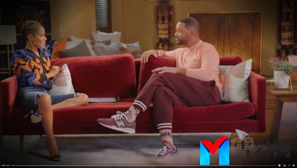 Will Smith and Jada Pinkett Smith sit on a red couch. 