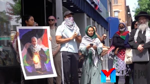 Protesters gather on the sidewalk around a photo of deceased Hamas leader Ismail Haniyeh.