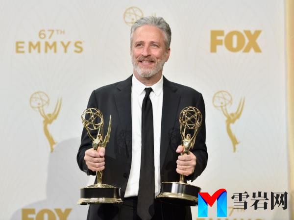 Jon Stewart smiling with Emmys. 