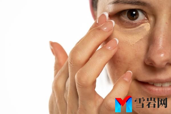 Middle-aged woman applying co<em></em>ncealer under her eye on a white background