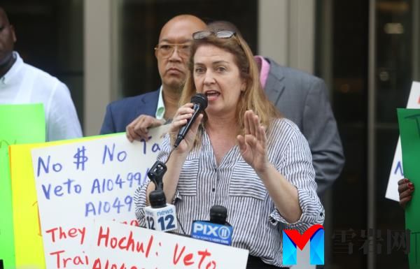 Maud Maron, Candidate for City Council District 1, speaking into a microphone during a protest outside NY State Governor Kathy Hochul